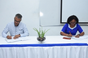 Mrs Mohideen and Mr Morel signing the agreement 